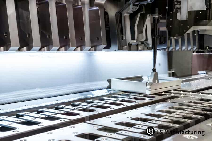 Una pressa stampa un foglio di alluminio spesso 1,2 mm in una staffa a L per l'assemblaggio di componenti automobilistici.