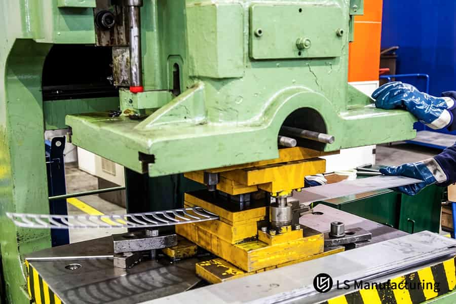 I lavoratori caricano i pezzi grezzi di acciaio nelle presse per la produzione di staffe per autoveicoli.